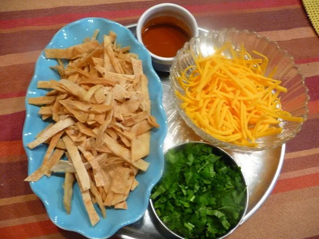 A tray of food with cheese, crackers and sauce.