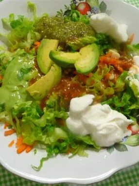 A bowl of salad with avocado and sour cream.