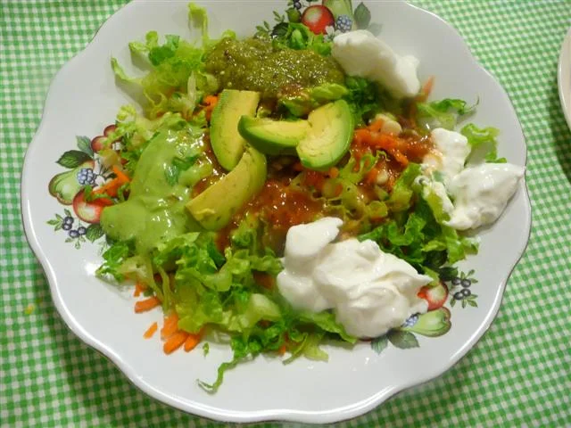 A bowl of salad with avocado and sour cream.