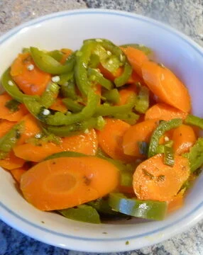 A bowl of sliced carrots and green peppers.