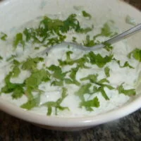 A bowl of food with greens and yogurt.