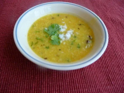 A bowl of soup with cilantro on the side.