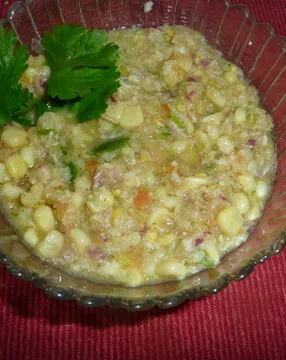 A bowl of corn salad with parsley on the side. Corn salsa