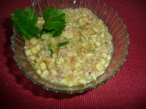 A bowl of corn salad with parsley on the side. Corn salsa