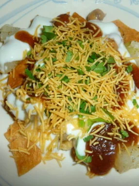 A plate of food with cheese, sour cream and chili.