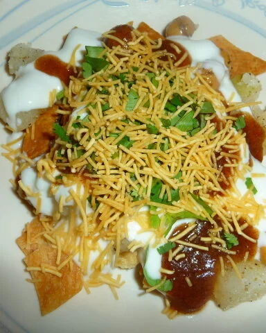 A plate of food with cheese, sour cream and chili.