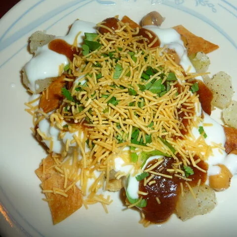 A plate of food with cheese, sour cream and chili.
