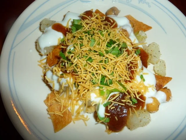A plate of food with cheese, sour cream and chili.