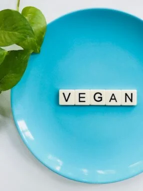 A plate with the word vegan spelled out in scrabble tiles.